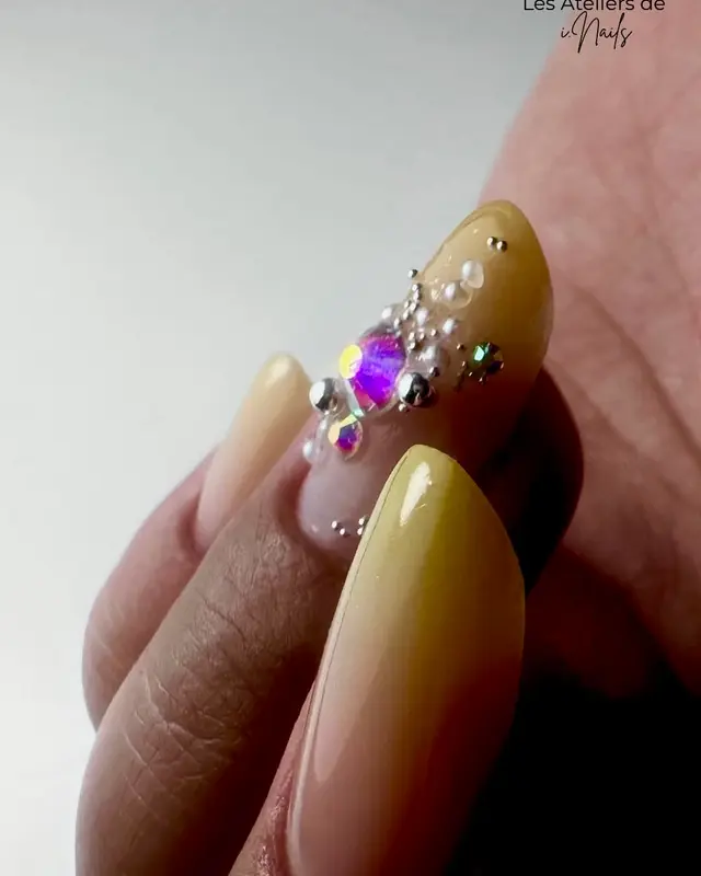 Ongles en amande dégradé jaune, strass et perles sur l’annulaire